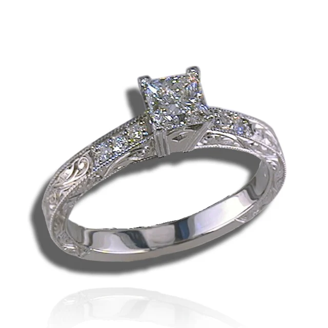 Square-centred diamond ring with diamond-set shoulders, engraved scrolls and fine beaded borders.