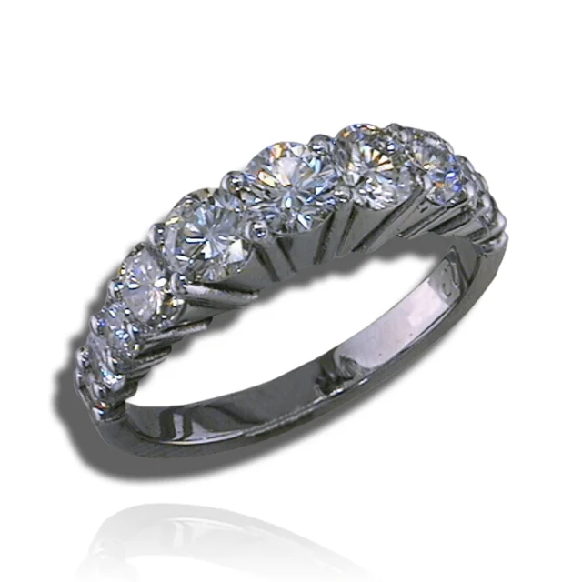 Graduated round diamonds in open prong settings across the upper half of a polished band.