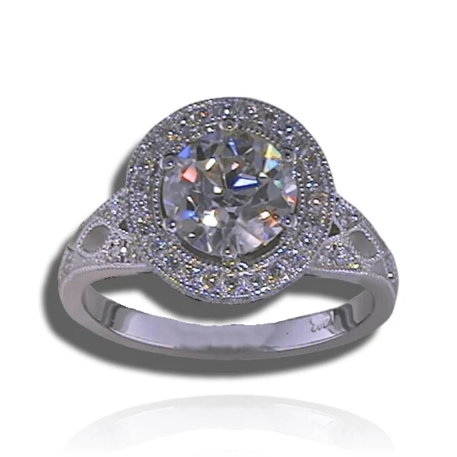 Round centre stone surrounded by a diamond halo, with openwork shoulders and fine beaded edges.