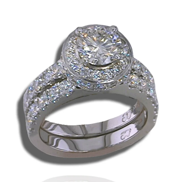 Round centre stone in a raised diamond halo above split, diamond-set shoulders.