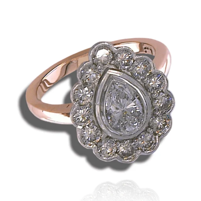 Bezel-set pear centre stone within a scalloped diamond halo on a rose-coloured band.